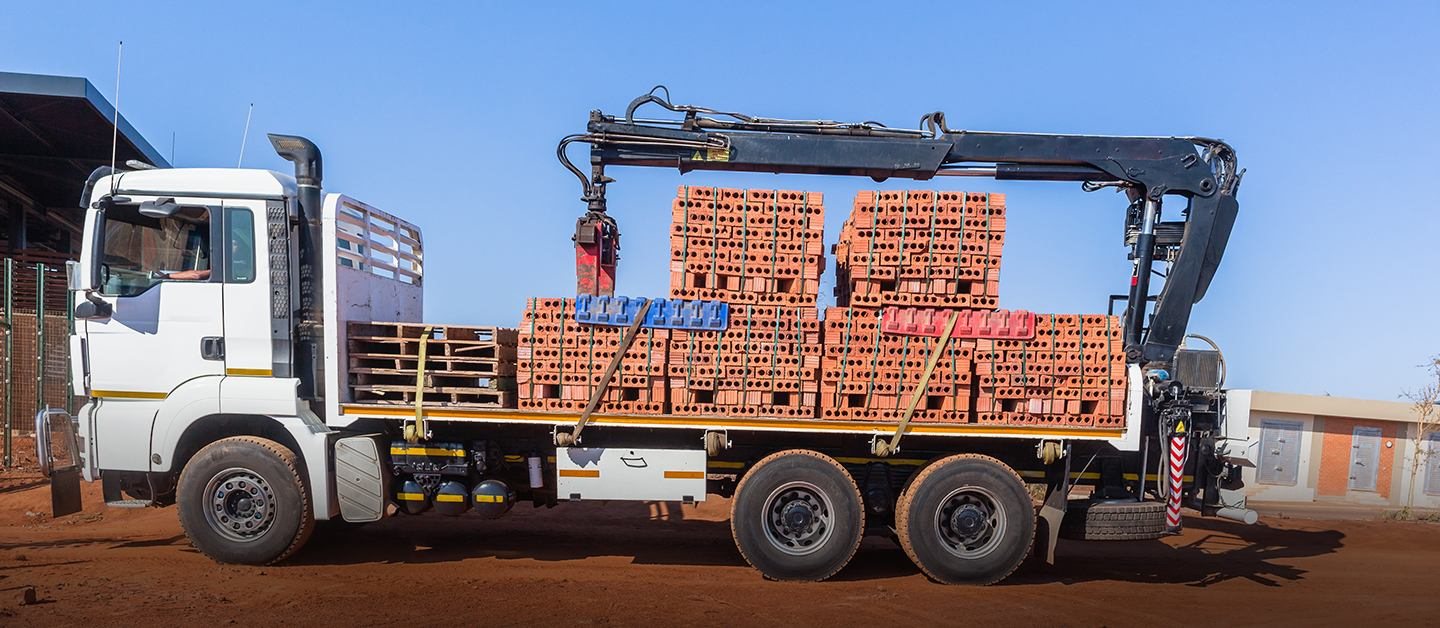 Crane truck loaded with bricks at a supply yard