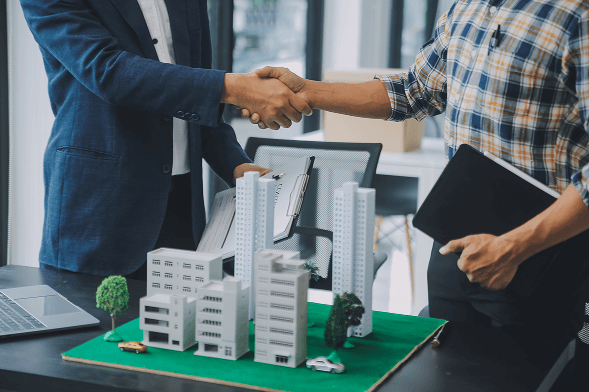 Client and contractor shaking hands over a building model